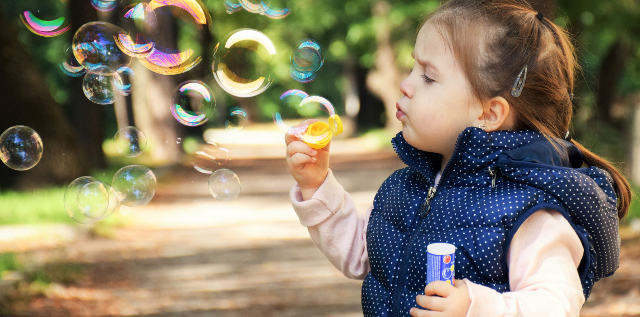 A young girl is blowing bubbles